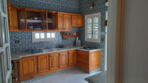 a kitchen with wooden cabinets and a stove in it at Maison Mira in Bizerte