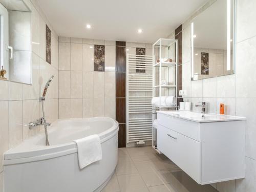 a white bathroom with a tub and a sink at Gästehaus Inntal in Radfeld