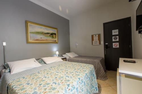 a bedroom with two beds and a picture on the wall at K3 RESIDENCE Cozinha Compartilhada in Campinas