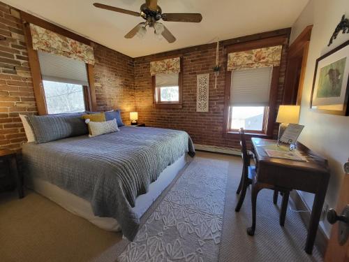 a bedroom with a bed and a desk and windows at Bross Hotel B & B in Paonia