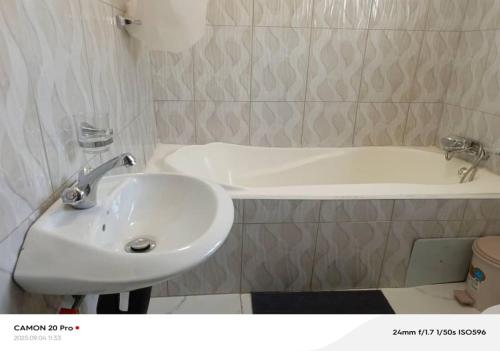 a bathroom with a sink and a bath tub at Raneziah Guesthouse in Kasane