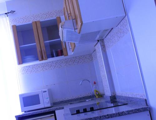 a kitchen with a sink and a microwave at Appartement dépaysante T1B in Tarrafal