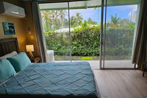 a bedroom with a bed and a large window at Ocean Views • Private Balcony + Prime Location in Hilo