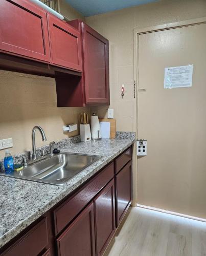 a kitchen with red cabinets and a sink and a door at Oceanfront Views • Balcony + Top Hilo Location in Hilo