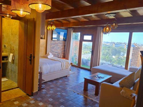 a bedroom with a bed and a living room with a couch at studio Azur rooftop with ocean view terrace privé in Essaouira