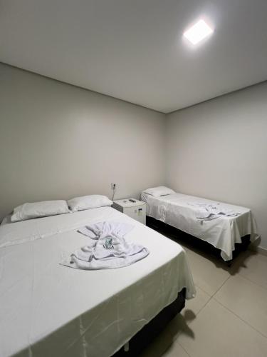 two beds in a room with white walls at Villa Hospedagem in Palmas