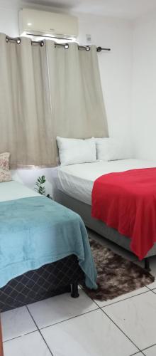 a bedroom with two beds with red and blue sheets at Bozena Beach Stay in Itacaré