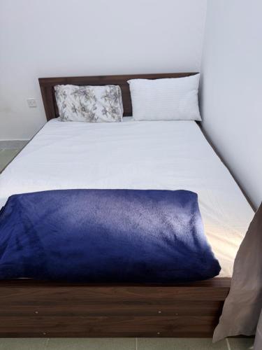 a bed with a blue blanket on top of it at Happy House in Al Ain