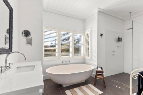 a white bathroom with a tub and a window at Mulgrave House in Bellawongarah