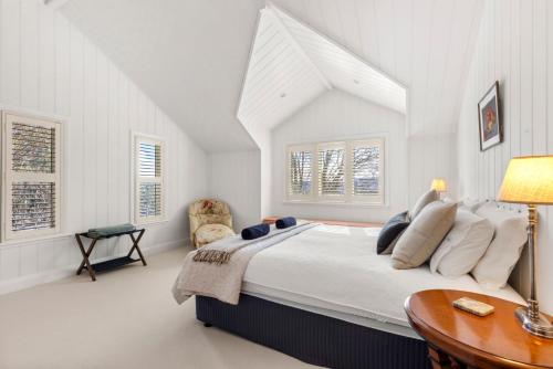 a white bedroom with a large bed and a table at Mulgrave House in Bellawongarah