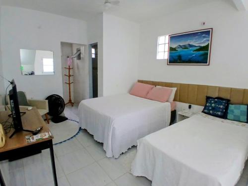 a hotel room with two beds and a television at Hospedagem da Lu in Paraty