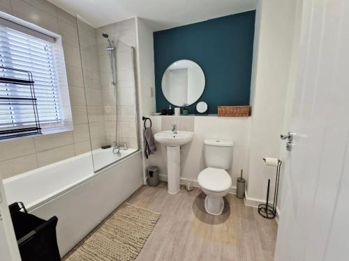 a bathroom with a toilet and a sink and a mirror at Gatwick Cozy Stopover 4 bedroom house with free Parking in Copthorne