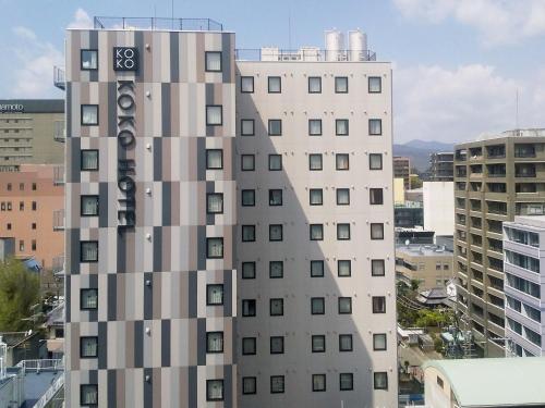 a tall white building with a sign on it at KOKO HOTEL Kumamoto Kamitori - formerly Hotel Wing International Select Kumamoto in Kumamoto