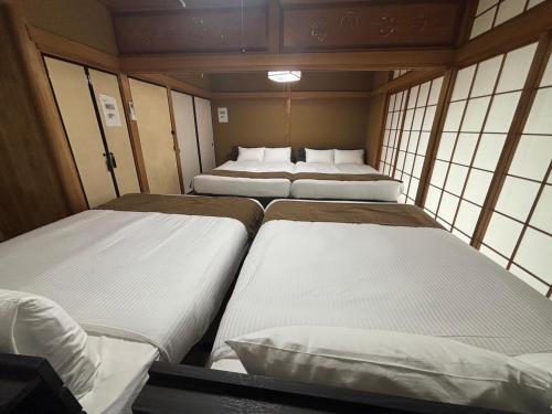 a group of three beds in a room with windows at HoTTOSTAY矢田 in Nagoya