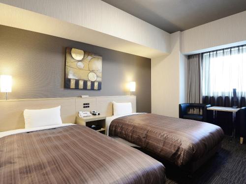 a hotel room with two beds and a table at Hotel Route Inn Grand Asahikawa Ekimae in Asahikawa