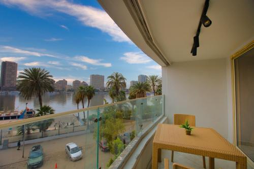 a balcony with a view of a river and palm trees at Cairo Homes Nile View Studios Manial in Cairo