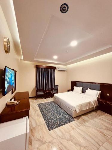 a bedroom with a bed and a desk and a television at كاسا للشقق المخدومة 2 in Dammam