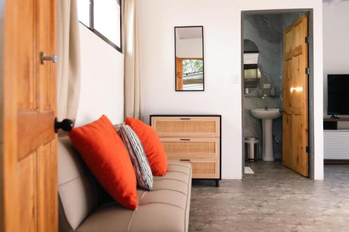 a living room with a couch with orange pillows at Nosara Hotel Playa Garza in Garza