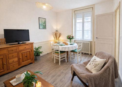 a living room with a table and a tv at Gîte Le Repos de Merlin - Paimpont, Forêt de Brocéliande in Paimpont