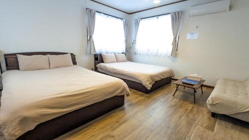 a bedroom with two beds and a chair in it at Guest House Tatara in Yasugi
