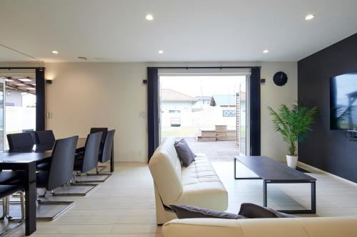 a living room with a couch and a table and chairs at The Garden Villa 九十九里ー遊び充実の海近リゾート別荘を最大15名で一棟貸切 in Shirako