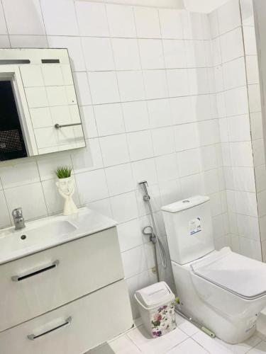 a white bathroom with a toilet and a sink at Goat1 in Dakar