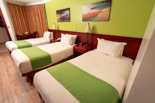 a hotel room with two beds with green walls at Quo Vadis Hotel in Loja