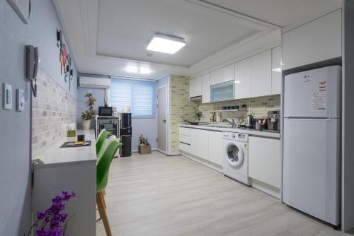a kitchen with white cabinets and a washer and dryer at DreamTrip Guesthouse in Incheon