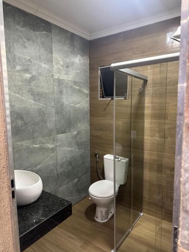 a bathroom with a toilet and a glass shower at Sítio com piscina em bh mirante do Sol in Santa Luzia