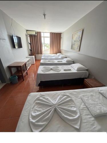 a row of four beds in a room at Hotel Lords in Brasília