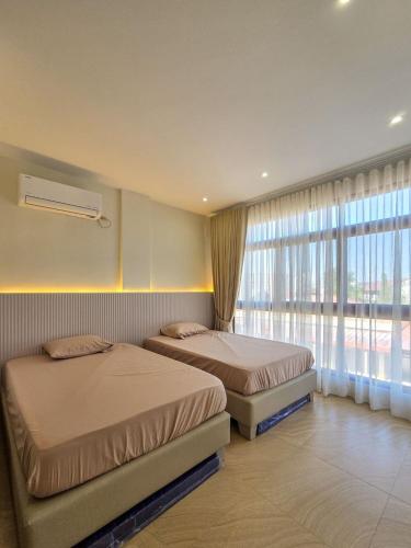 a bedroom with two beds and a large window at C Urban Villas 2 in Dau