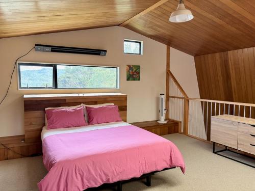 a bedroom with a bed with pink sheets and a window at Whangaroa Barn in Whangaroa