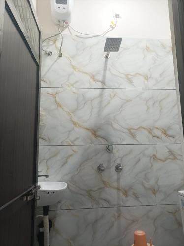 a bathroom with a marble shower with a sink at आदिनाथ गेस्ट हाउस in Ujjain