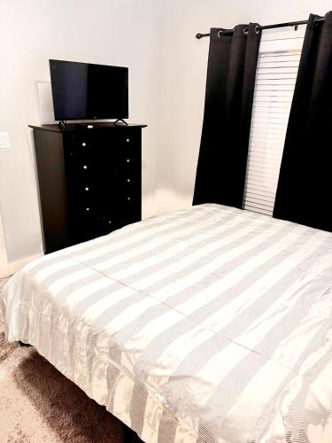 a bedroom with a bed and a dresser with a television at New! 1 Bed 1 Bath Medical Center NRG Area Middle of Everywhere in Houston