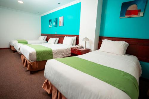 a hotel room with three beds and a blue wall at Quo Vadis Hotel in Loja
