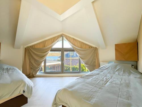 a bedroom with two beds and a large window at Wellness Escape with Private Sauna in Sibculo