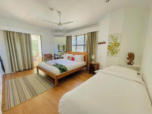 a bedroom with two beds and a large window at Residence71Nadi Fiji in Nadi
