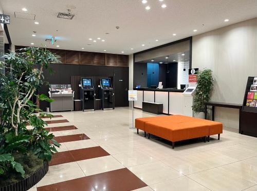 a store lobby with an orange ottoman in the middle at Richmond Hotel Tokyo Musashino in Musashino