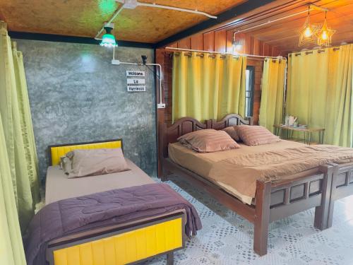 two beds in a room with yellow curtains at Homestay Baan Ik-ka-lik in Nan
