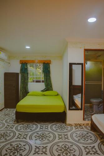 a bedroom with a green bed and a mirror at POSADA NATIVA DERMA´S INN in San Andrés