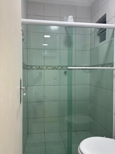 a bathroom with a glass shower with a toilet at Suíte sossego in Rio das Ostras