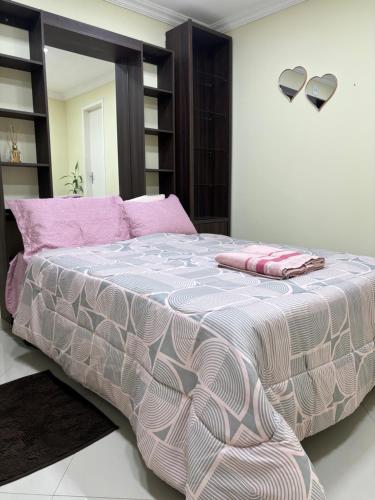 a bedroom with a large bed with pink and white sheets at Suíte sossego in Rio das Ostras
