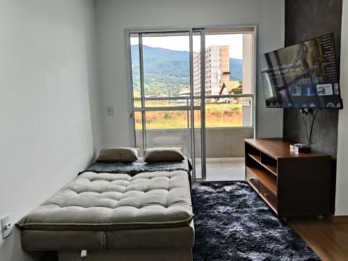 a living room with a couch and a large window at Paraiso da Mantiqueira - Staffy House Extrema in Extrema