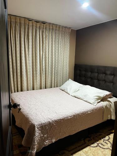 a bed in a bedroom with a window with curtains at Palmeras house in Ica