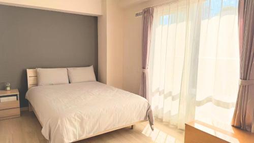 a bedroom with a bed and a large window at hotel gala city only 5 mins to Kokusai Street 24 square meters room in Naha