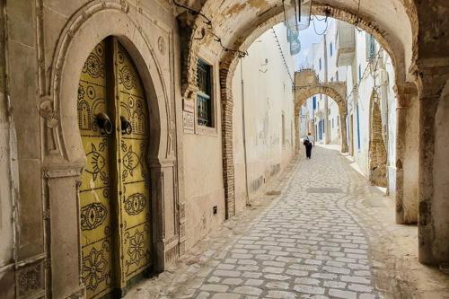 a man walking down an alley with an archway next to a door at Dar D'Art in Tunis