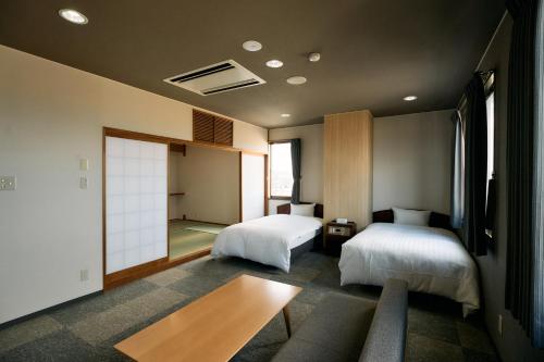 a bedroom with two beds and a table in it at COZY HOTEL NUKUI shimanami in Imabari