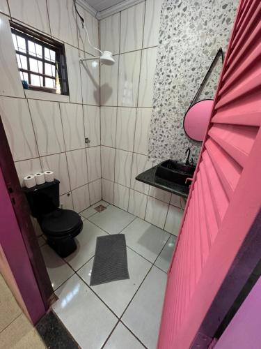 a bathroom with a black toilet and a sink at Quarto próximo ao parque de exposição BR163 in Dourados