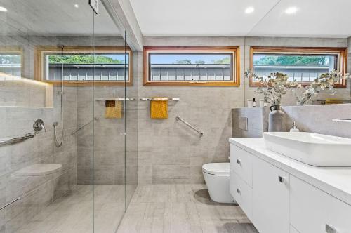 a bathroom with a shower and a toilet and a sink at Villa Syrene Pool and Spa Retreat in Rye