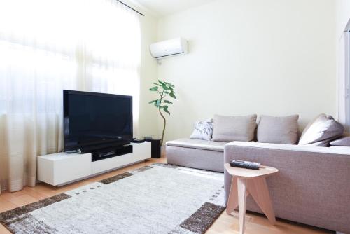 uma sala de estar com um sofá e uma televisão de ecrã plano em Luxury New House em Tóquio